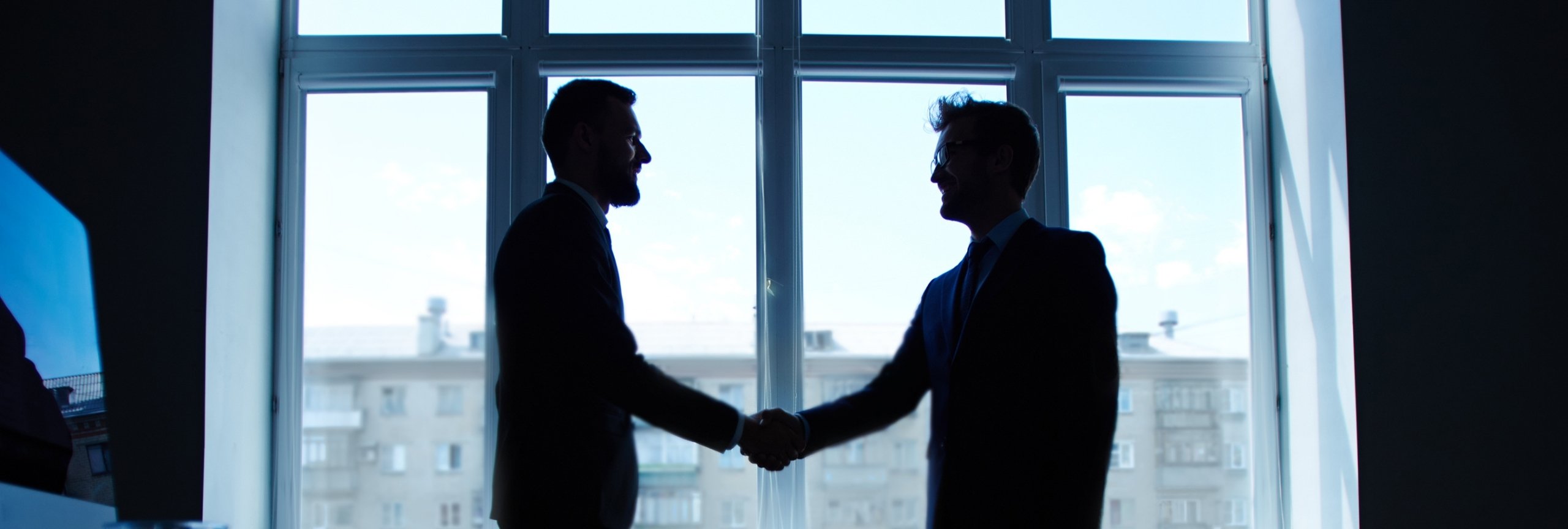 Two business silhouettes shaking hands, symbolizing a partnership in HR Tech and AI recruitment software.